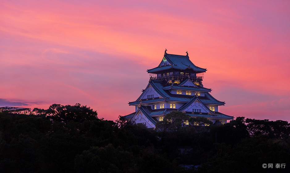 写真１．夕焼けに染まる大阪城天守閣。日暮れとともにライトアップが始まる